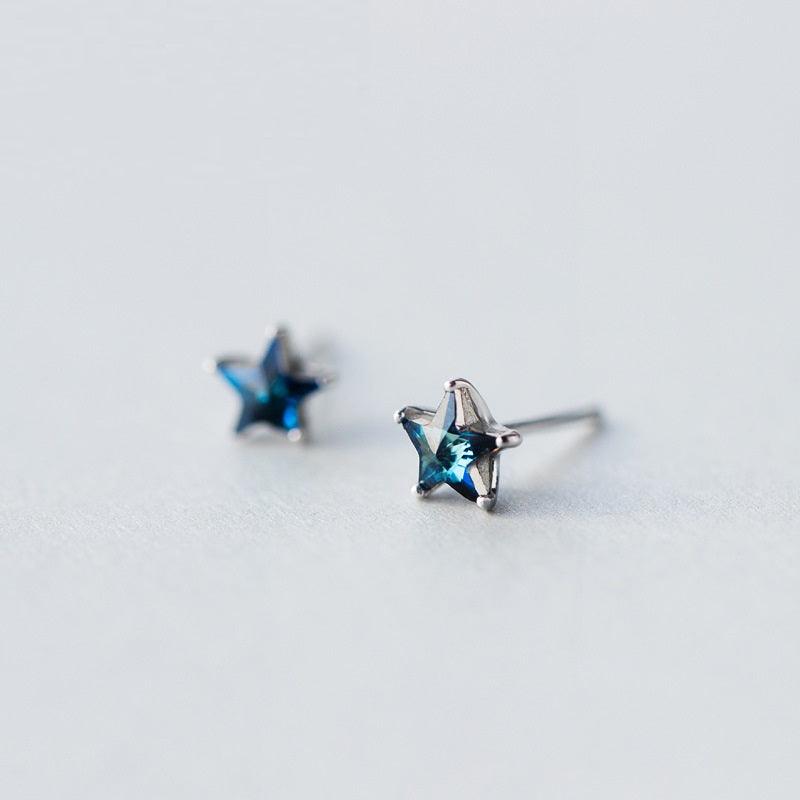 Delicate star-shaped stud earrings with sparkling blue gemstones set in silver, offering a celestial-inspired design