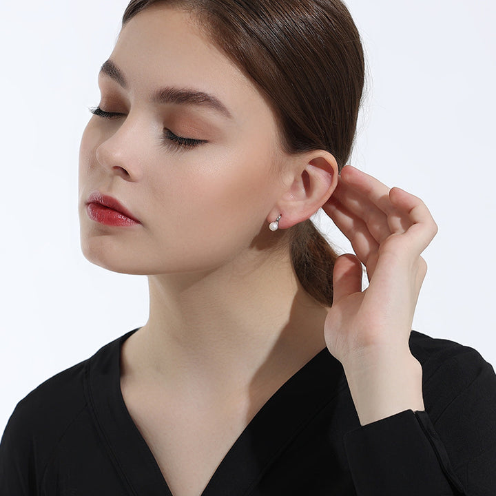 Model showcasing elegant pearl stud earrings, paired with a sleek black outfit for a timeless and refined look.