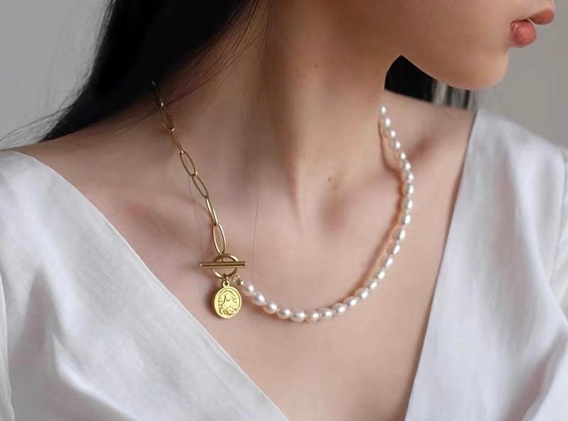 Pearl necklace with gold coin charm and toggle clasp worn over a white v-neck top