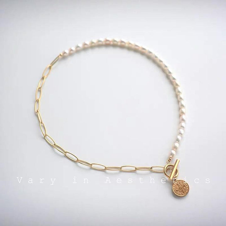 Stylish pearl and gold chain necklace with coin charm and toggle clasp on a white background